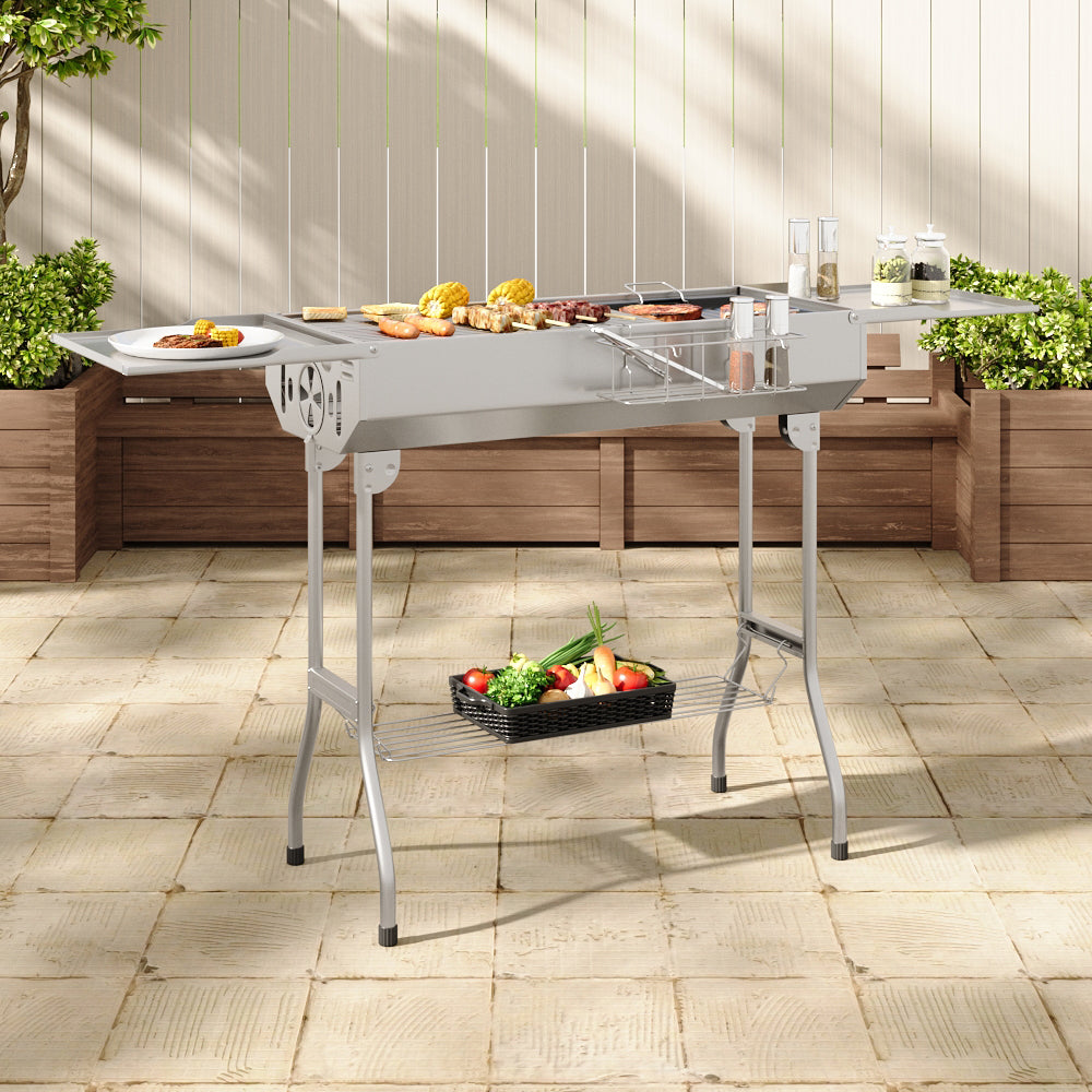 Charcoal barbecue grill in garden setting with picnic setup – ideal for outdoor cooking and summer BBQs