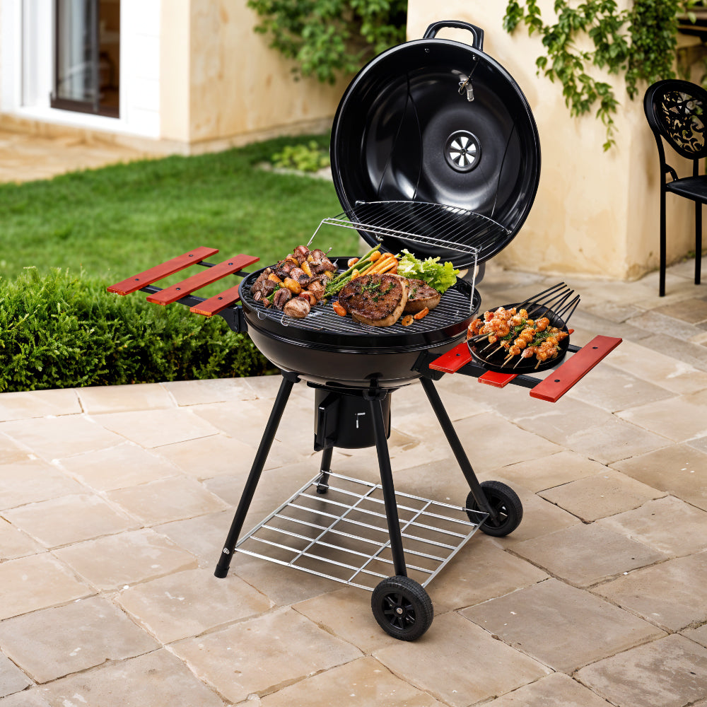 Garden scene with black kettle charcoal BBQ grill – outdoor portable barbecue in use for backyard grilling