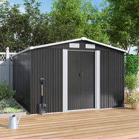 Black metal garden shed with a white door on a wooden deck, surrounded by greenery.