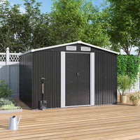 Closed black metal shed on patio floor, placed against wooden garden fence