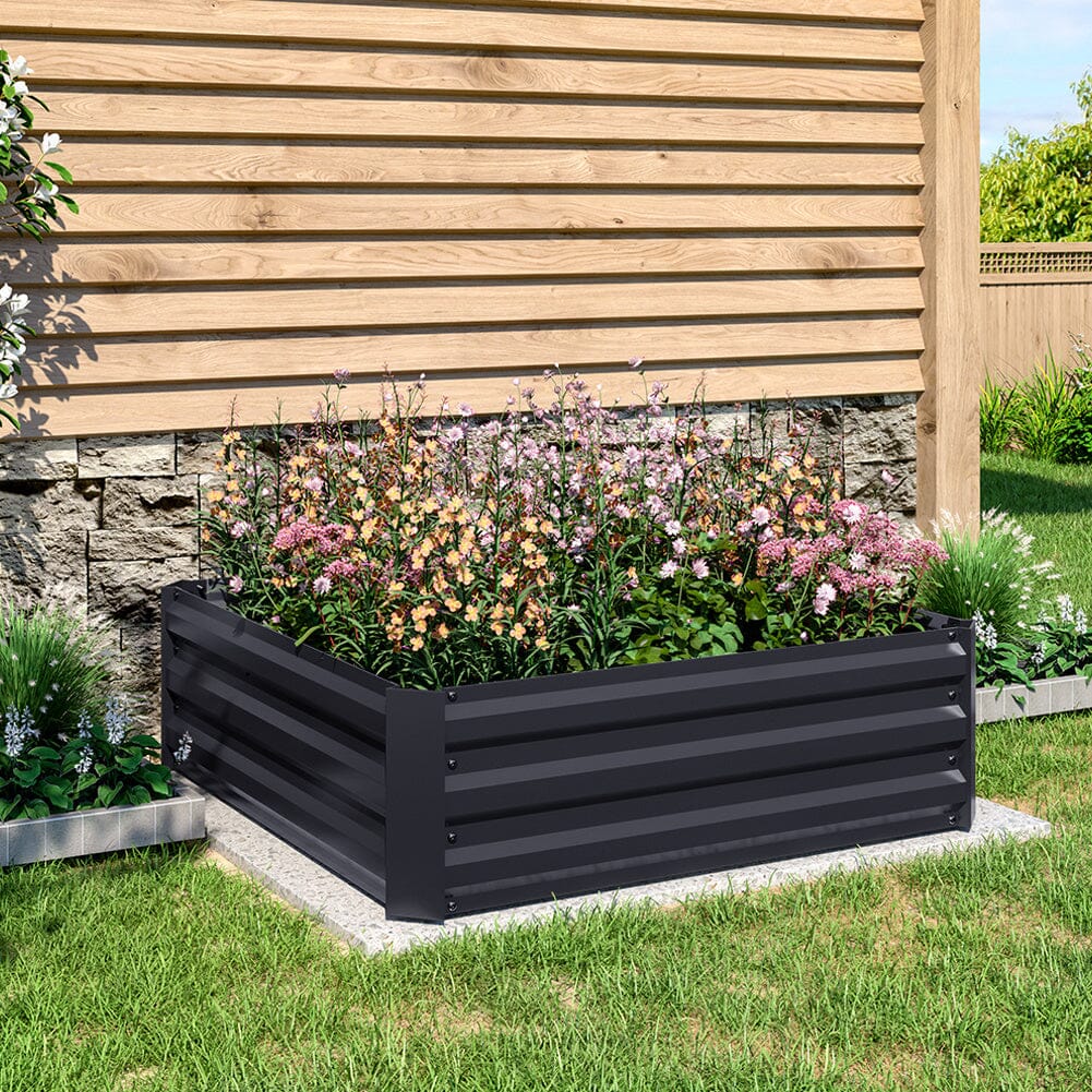 Medium Black Galvanized Steel Square Raised Garden Bed in a lush garden filled with thriving plants and flowers